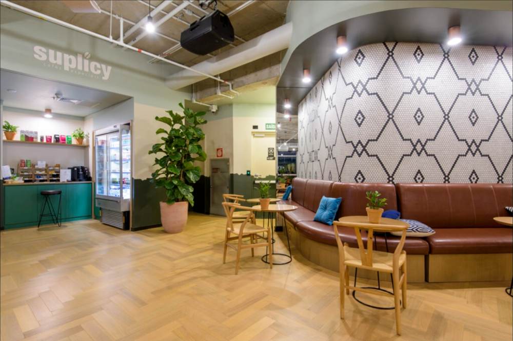 Espaço comercial com balcão, revestimento geométrico e mesas de madeira